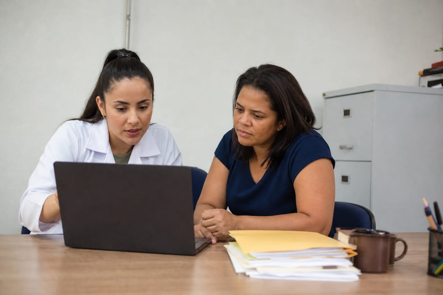 Nutricionista e servidora da secretaria de educação avaliando um sistema no notebook em um escritório público